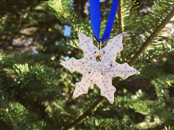 White snowflake ornament with small blue polkadot design. Close up detail image.